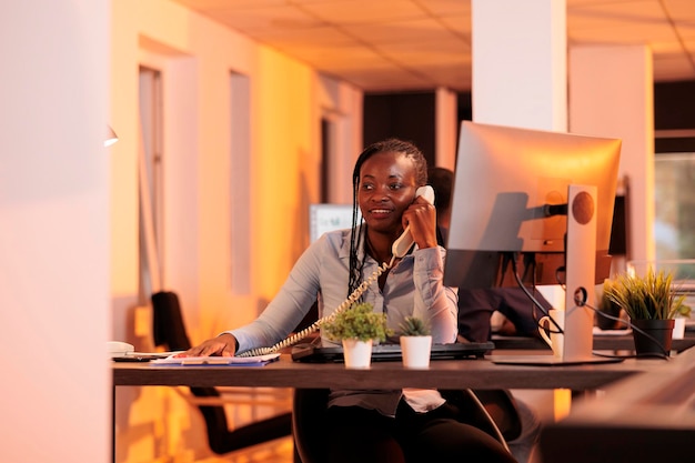 Secretária de escritório atendendo telefone fixo para falar sobre pesquisa de negócios com gerente de projeto. conversando remotamente na linha telefônica do escritório, conversando sobre o relatório de e-mail.