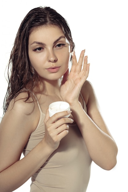 Segredos da juventude. Mulher jovem e bonita parede branca. Cosméticos e maquiagem, tratamento natural e ecológico, cuidados com a pele.