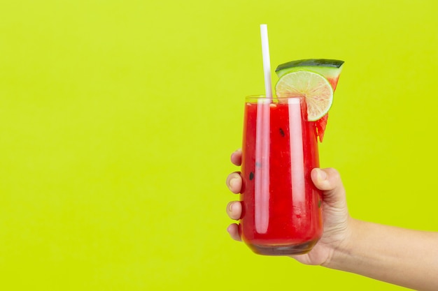 Foto grátis segurando a melancia com suco de limão no tempo quente do verão na parede amarela.