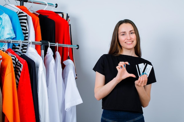 Segurando cartões de crédito menina si mostrando gesto de tamanho no fundo da roupa