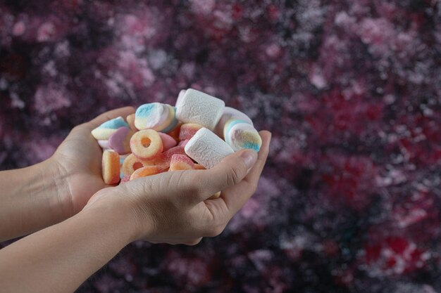 Segurando marshmallow e mistura de jujubas à mão.