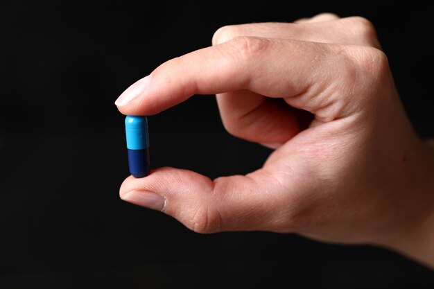Segurando uma pílula médica azul na mão.