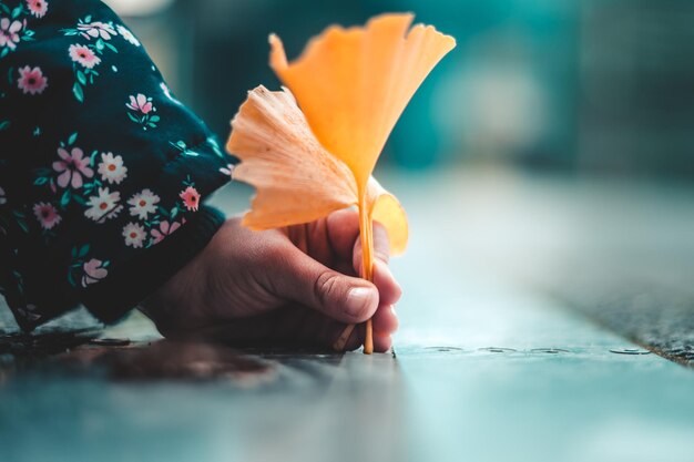 Seletivo da mão de uma menina escrevendo com uma folha de laranja no chão