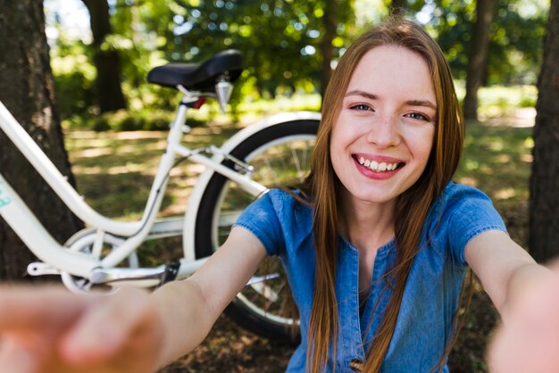 Selfie de uma mulher sorridente ao lado de bicicleta