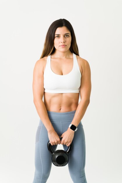 Sem desculpas. Retrato de uma linda mulher forte com um abdômen tonificado segurando um peso de kettlebell e fazendo contato visual enquanto se exercita