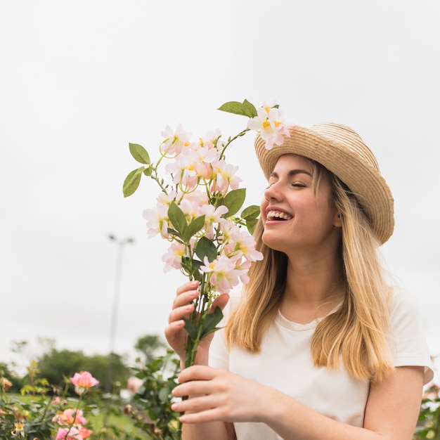Senhora alegre no chapéu com flores brancas