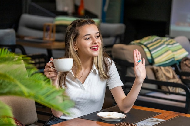 Senhora alegre segurando a xícara de café e apertando a mão de lado