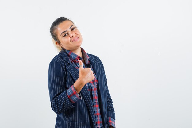 Senhora aparecendo o polegar na camisa, jaqueta e parecendo confiante, vista frontal