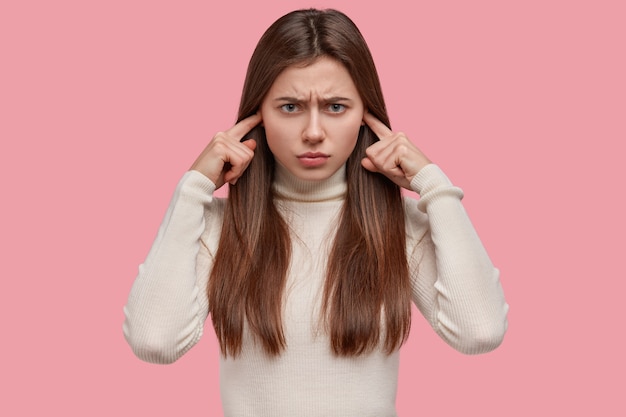 Senhora caucasiana infeliz estressante ignora algo desagradável, tapa os ouvidos, irritada com barulho alto, franze a testa, tem expressão sombria