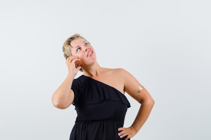 Foto grátis senhora charmosa posando como se estivesse fazendo uma ligação com uma blusa preta e parecendo falante