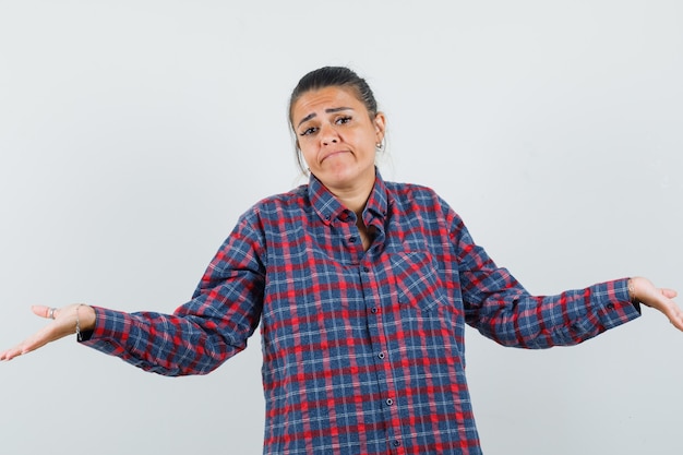 Senhora de camisa casual, mostrando um gesto desamparado e parecendo confusa, vista frontal.