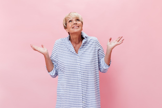 Senhora de camisa xadrez posa com mal-entendido em fundo rosa