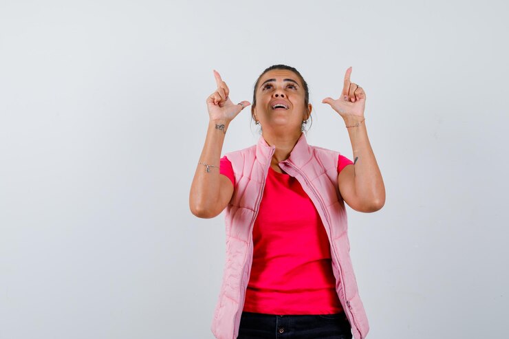 Foto grátis senhora de camiseta, colete apontando para cima e parecendo agradecida