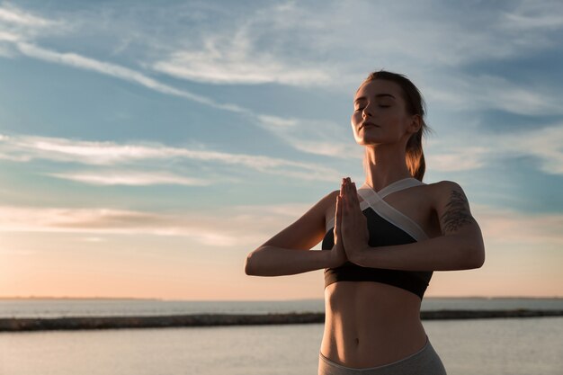 Senhora de esportes na praia fazer meditar exercícios.