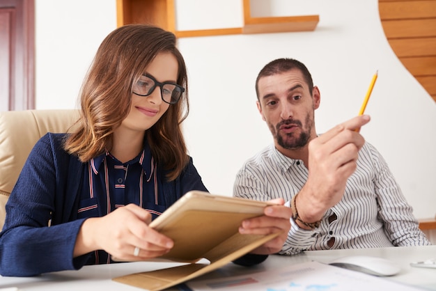 Senhora de negócios alegre lendo o relatório sobre tablet