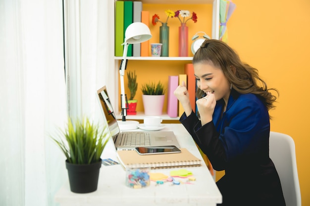 Senhora de negócios alegre trabalhando no laptop no escritório