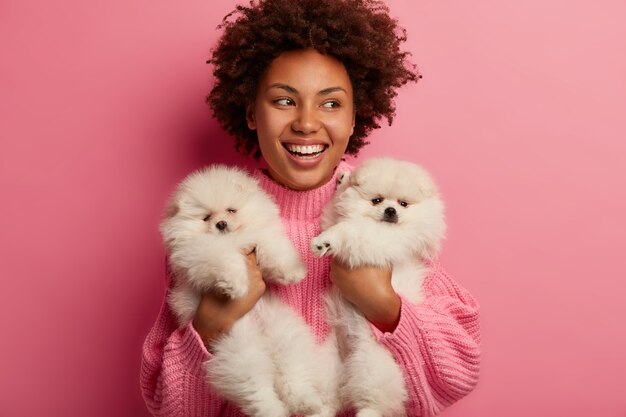 senhora de pele escura mantém os lábios arredondados, quer beijar bichinho adorável, brinca com cachorrinho