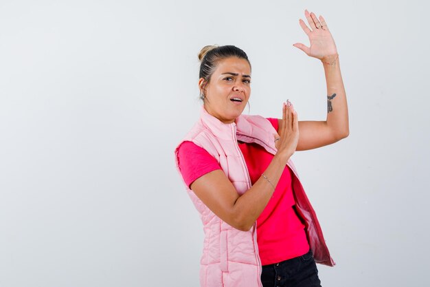 Senhora em pé em pose de luta com camiseta, colete e parecendo confiante