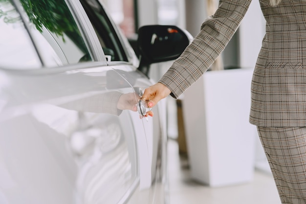 Senhora em um salão de automóveis. Mulher comprando o carro. Mulher elegante em um terno marrom.