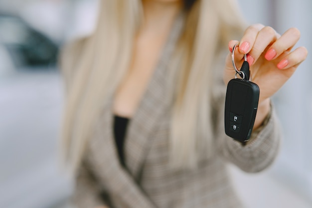 Senhora em um salão de automóveis. Mulher comprando o carro. Mulher elegante em um terno marrom.