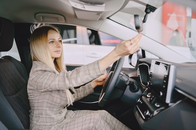 Senhora em um salão de automóveis. mulher comprando o carro. mulher elegante em um terno marrom.