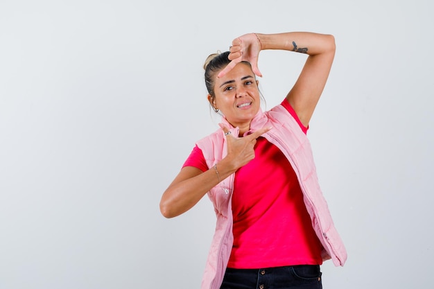 Senhora fazendo gesto de moldura em camiseta, colete e parecendo alegre