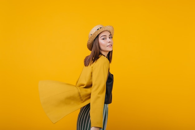 Senhora inspirada em posando de jaqueta amarela. Foto interna de modelo feminino despreocupado com chapéu de palha.