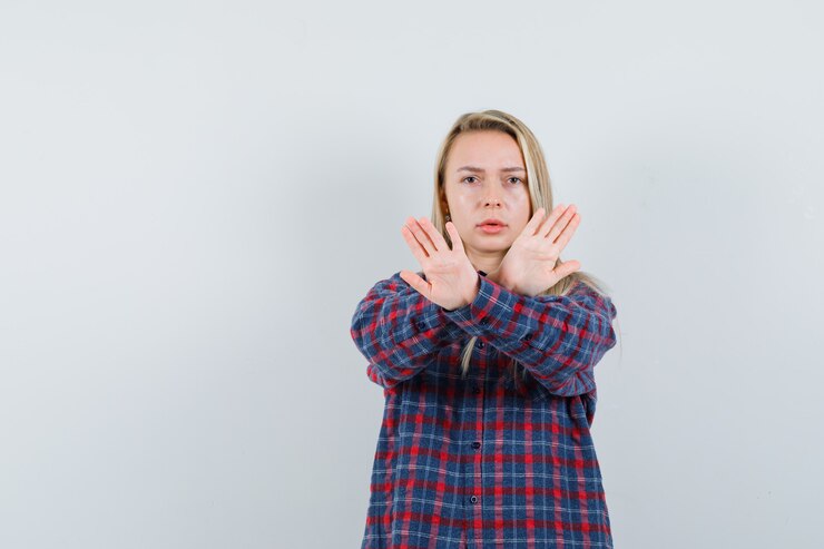 Foto grátis senhora loira de camisa casual, mostrando o gesto de parada e olhando sério, vista frontal.