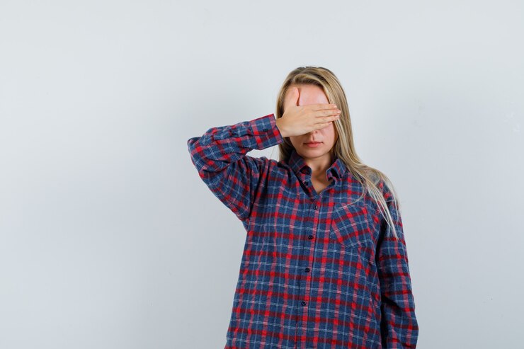 Foto grátis senhora loira de camisa casual, segurando a mão nos olhos e parecendo triste, vista frontal.
