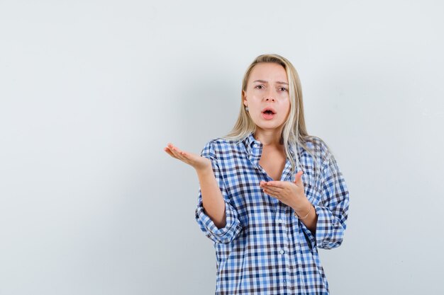 Senhora loira de camisa xadrez esticando as mãos em um gesto perplexo