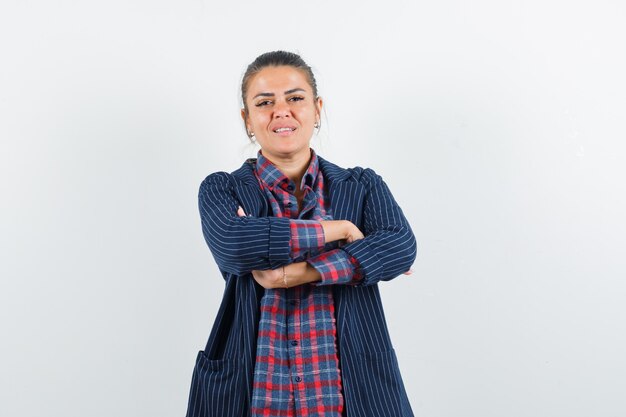 Senhora loira em pé com os braços cruzados na camisa, jaqueta e parecendo confiante. vista frontal.