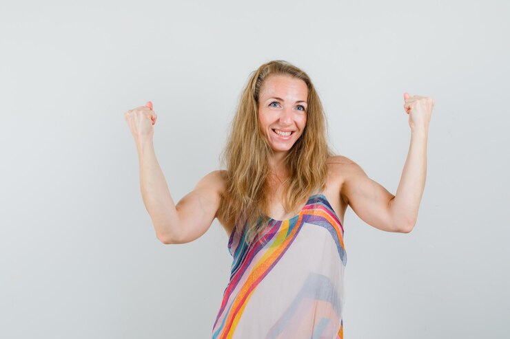 Foto grátis senhora loira mostrando o gesto de vencedor com vestido de verão e parecendo feliz.