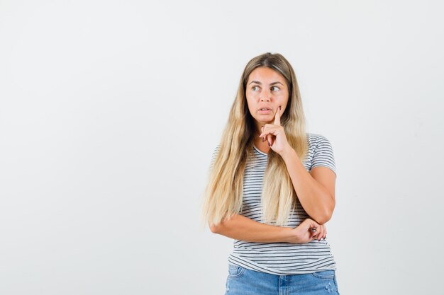 Senhora loira olhando de lado enquanto pensava em t-shirt e olhando pensativa, vista frontal.