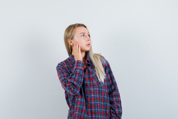 Senhora loira olhando para cima em uma camisa casual e parecendo focado. vista frontal.