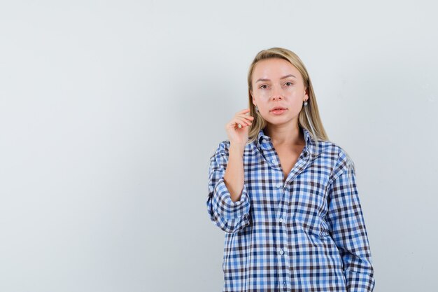 Senhora loira posando em pé com uma camisa casual e parecendo sensata