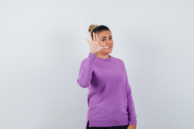 Senhora mostrando gesto de parada em blusa de lã e parecendo confiante