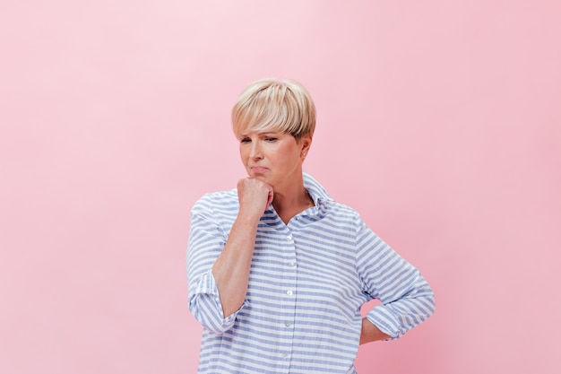 Senhora pensativa em poses de camisa xadrez em fundo rosa