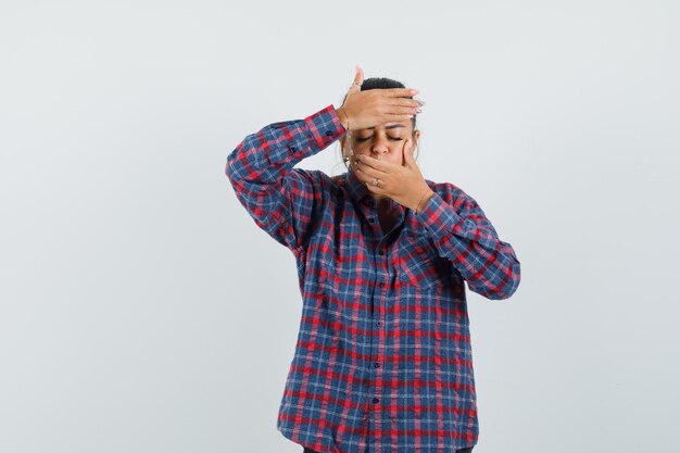 Senhora segurando as mãos nos olhos e boca em uma camisa casual e parecendo calma. vista frontal.