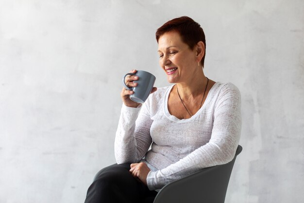 Senhora sênior positiva, segurando uma caneca