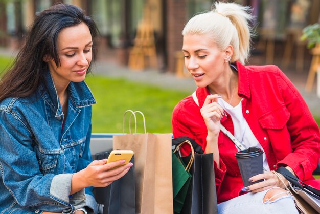 Senhoras com pacotes de compras, sentado no banco no parque