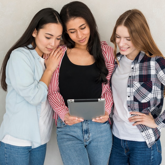 Senhoras em pé com tablet e olhando para ele