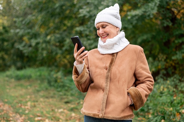 Sênior de baixo ângulo sorridente feminino olhando para o telefone