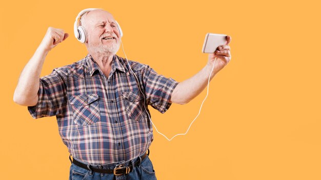 Sênior feliz assistindo vídeos de música no telefone
