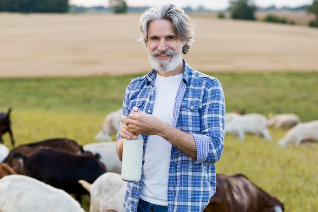 Foto grátis sênior segurando uma garrafa de leite de cabra em frente