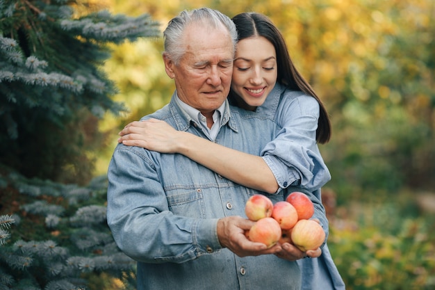 Senior sênior em pé em um jardim de verão com maçãs