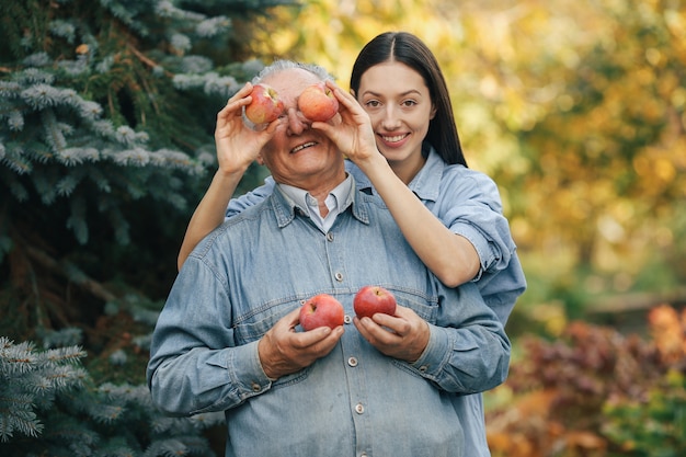 Senior sênior em pé em um jardim de verão com maçãs