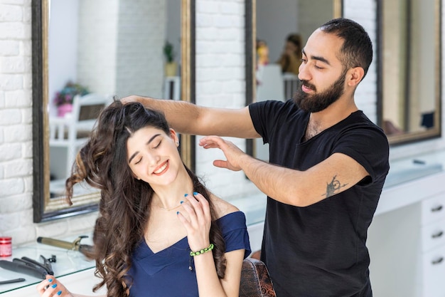 Sentado na barbearia e sorrindo enquanto Barber faz o cabelo dela Foto de alta qualidade