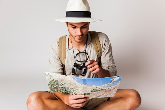 Foto grátis sentado turista olhando o mapa com lupa