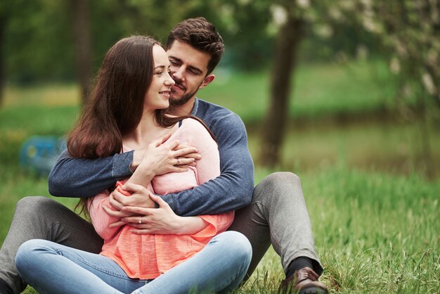 Sentados juntos ao ar livre na primavera. Jovem casal se abraçando