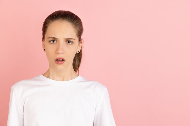 Sério, calmo e composto. Retrato de mulher jovem branca isolado na parede rosa do estúdio com copyspace.